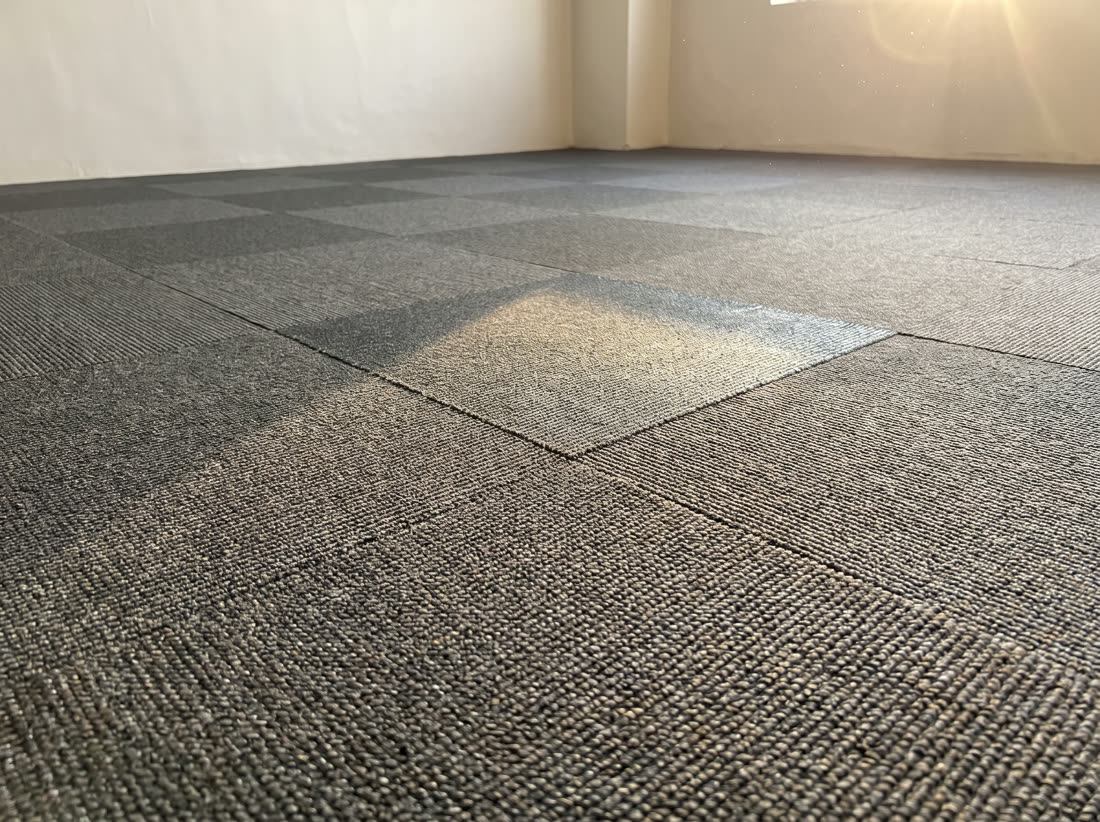 Charcoal loop pile carpet tiles laid in a grid with their seams visible.