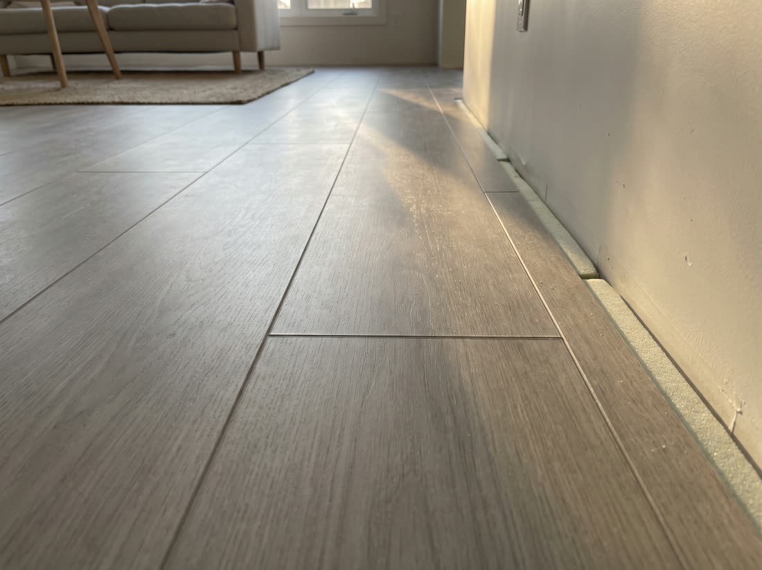 Pale grey wood look click plank vinyl with a crisp bevel between each plank.