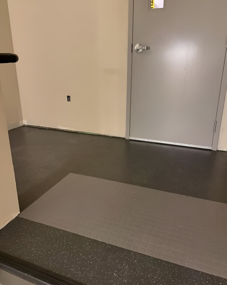 Dark speckled commercial vinyl flooring on a stairwell landing with a contrasting step tread.