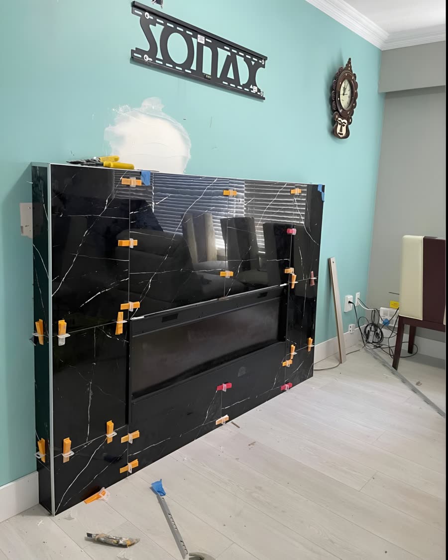Black marble effect fireplace tile being set on a feature wall.