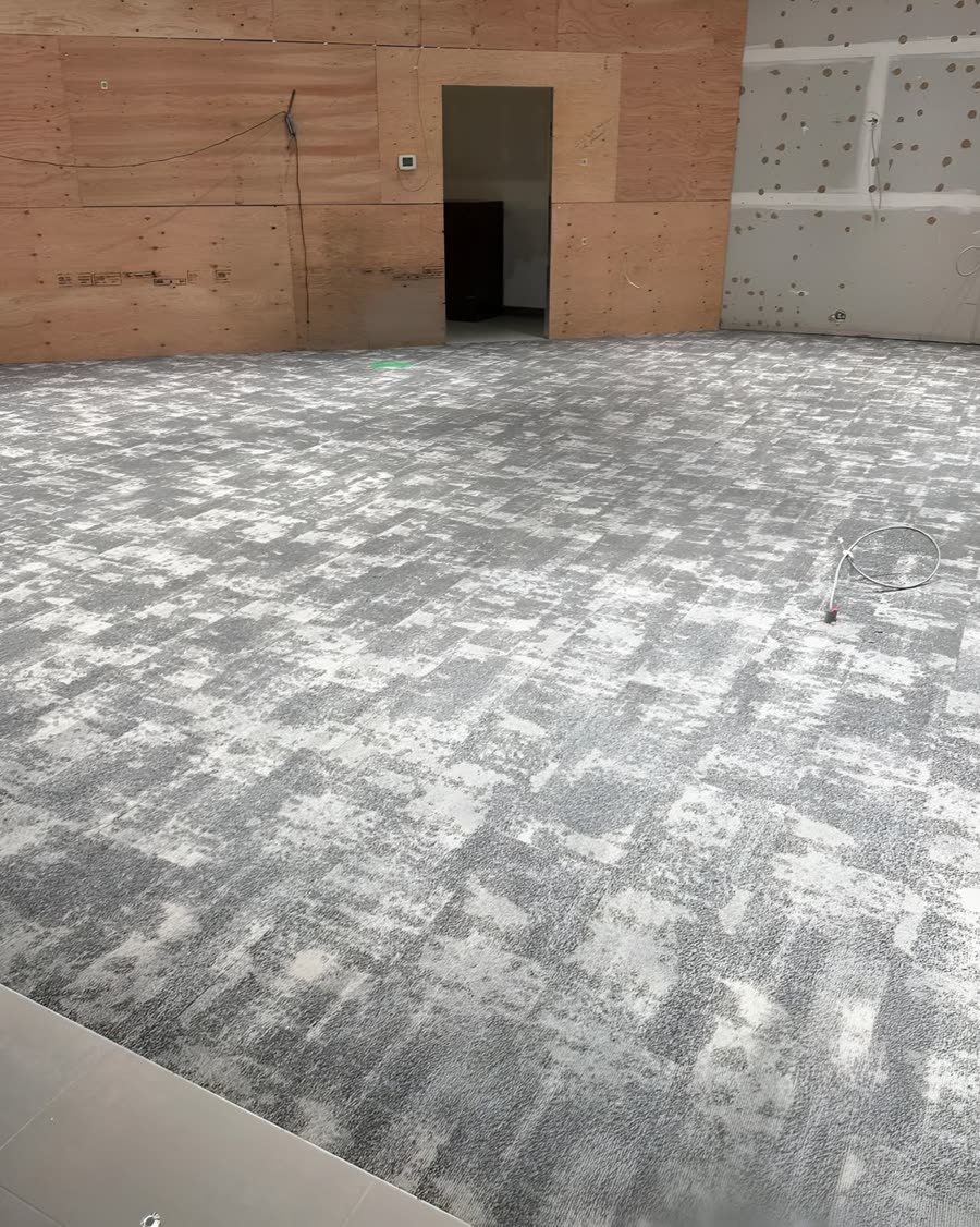 Patterned carpet tile being laid across a large commercial floor.